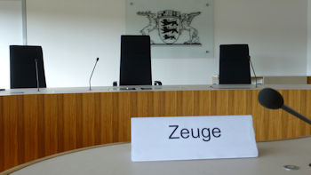 Foto eines Richtertisches im Landesarbeitsgericht Baden-Württemberg und im Hintergrund das Landeswappen